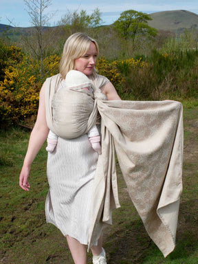 Woman with a baby in a woven wrap with a natural background