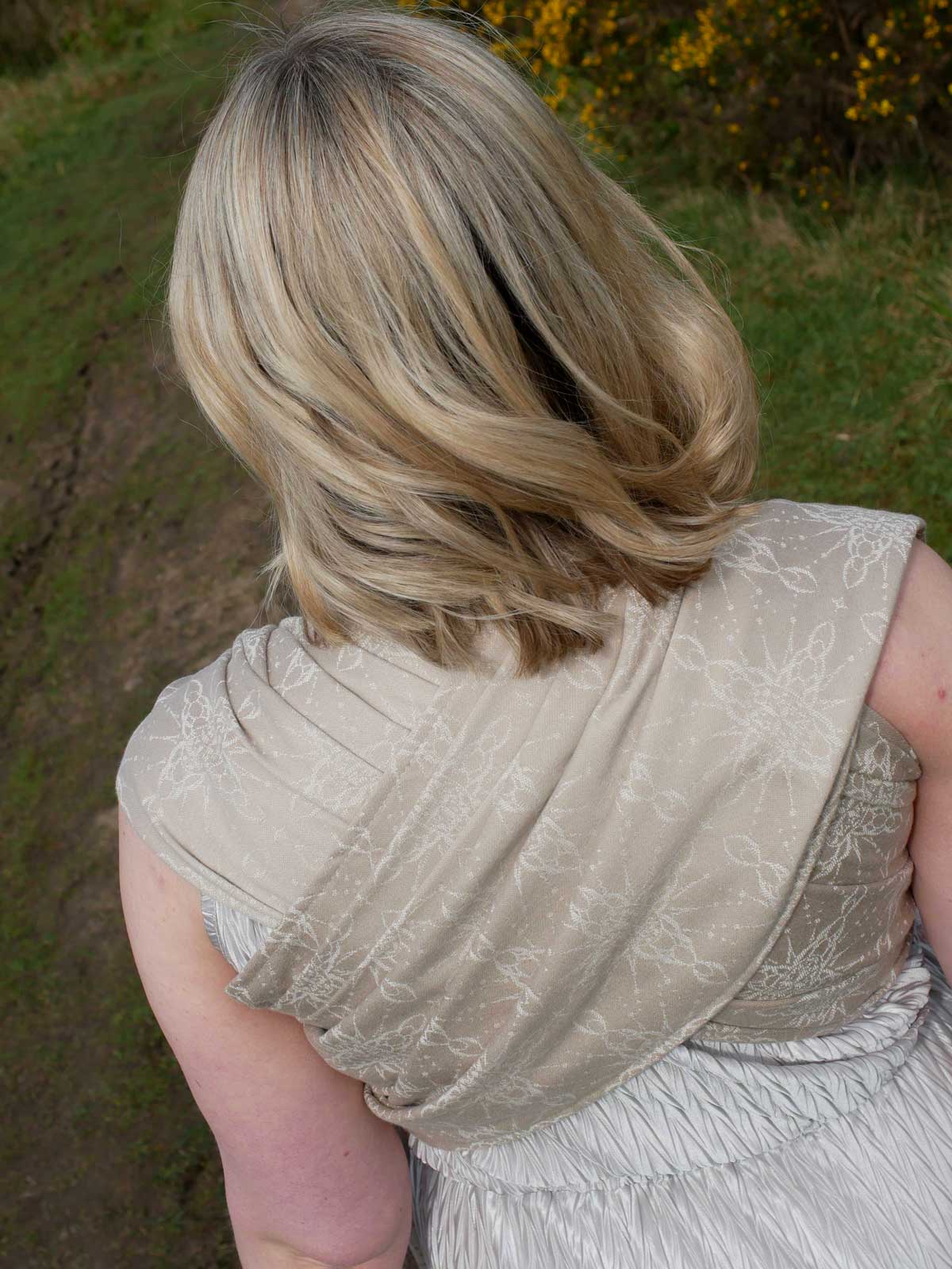 Woman with a baby in a woven wrap with a natural background