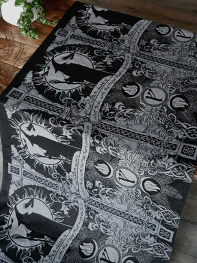 Black and silver patterned fabric with Lord of the Rings designs on a wooden surface.