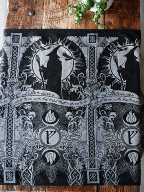 Black and silver patterned fabric with Gandalf design on a wooden surface