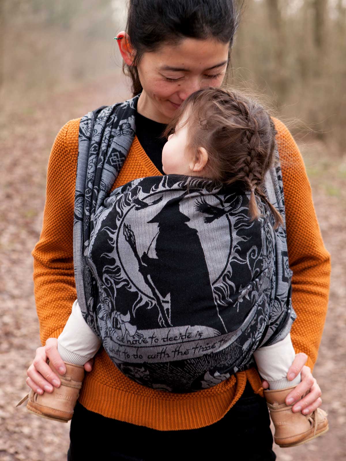 Woman carrying a child in a baby woven wrap outdoors