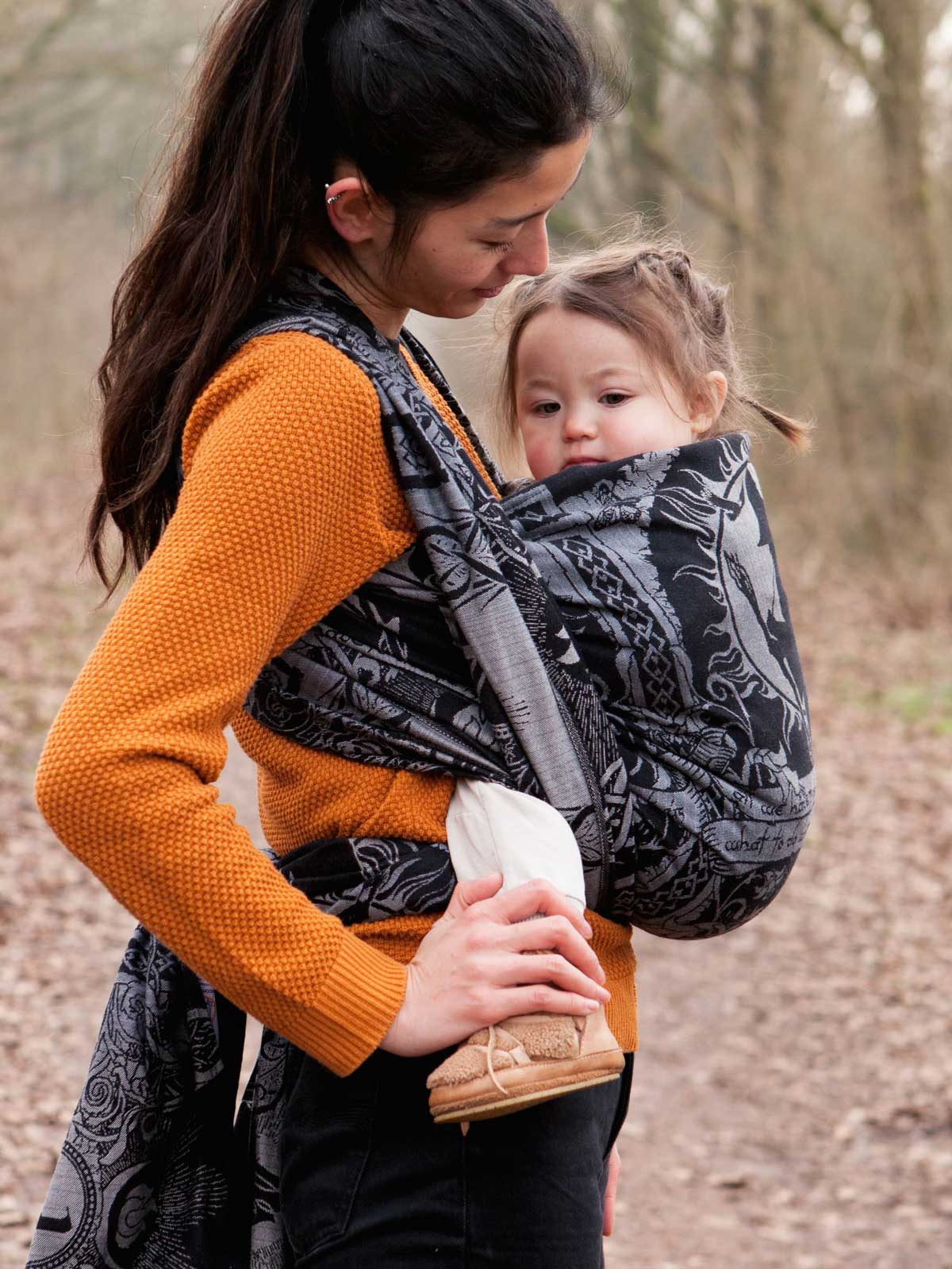 Woman carrying a child in a baby wrap outdoors