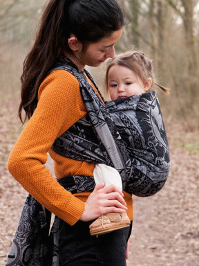 Woman carrying a child in a baby wrap outdoors