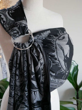 Mannequin wearing a black and gray patterned ring sling with a silver ring on a white background