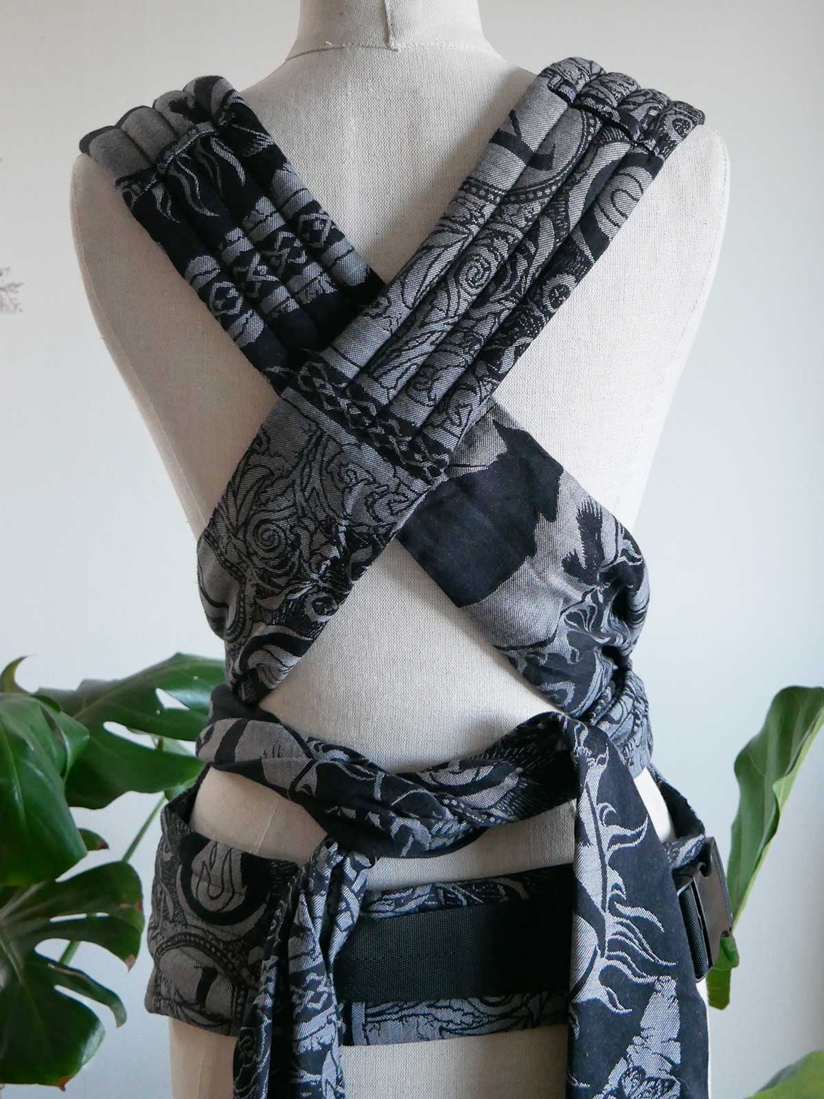 Black and gray patterned baby carrier on a mannequin with a white background