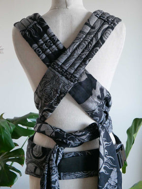 Black and gray patterned baby carrier on a mannequin with a white background