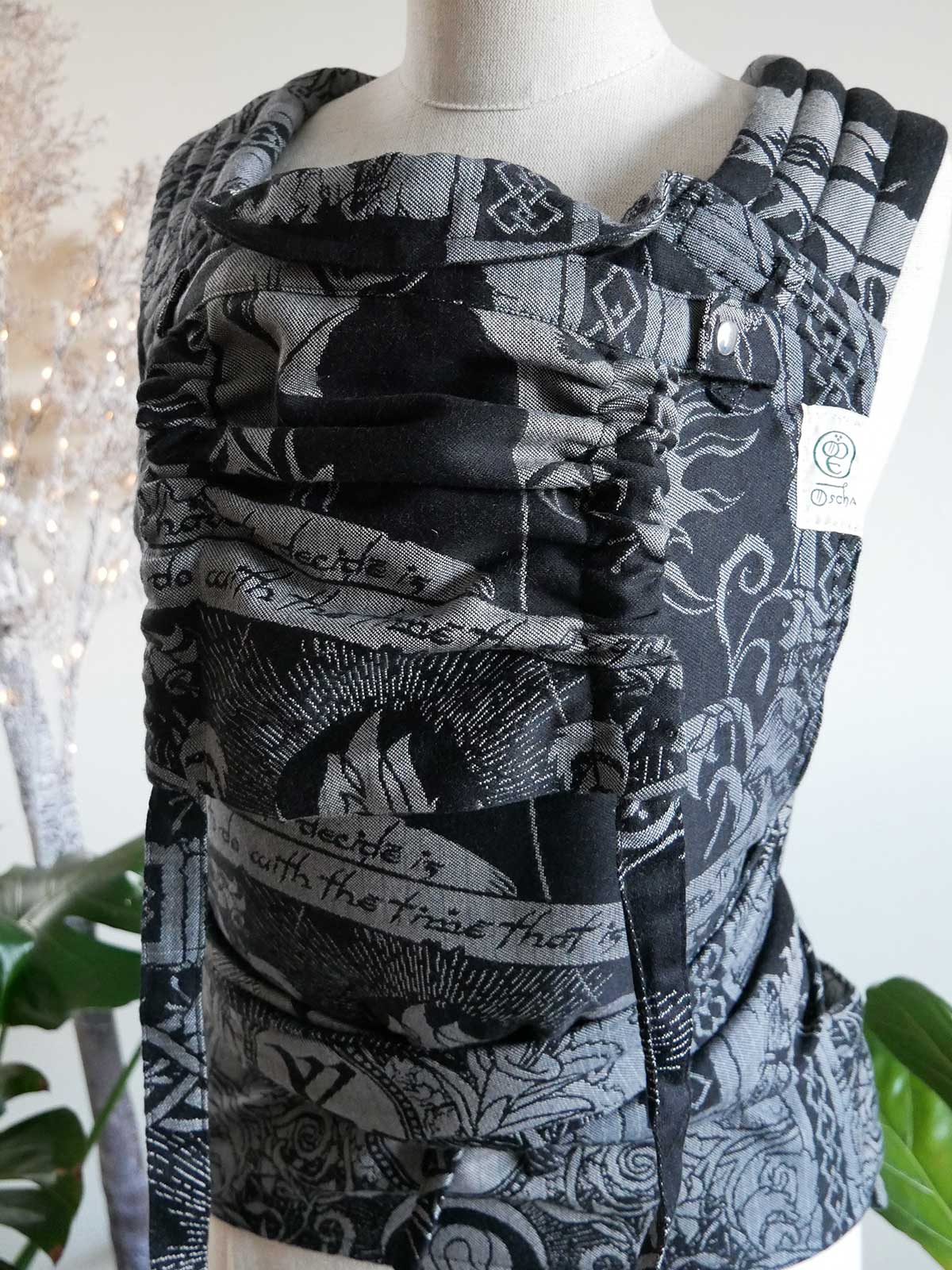 Black and silver patterned baby carrier on a mannequin against a white background