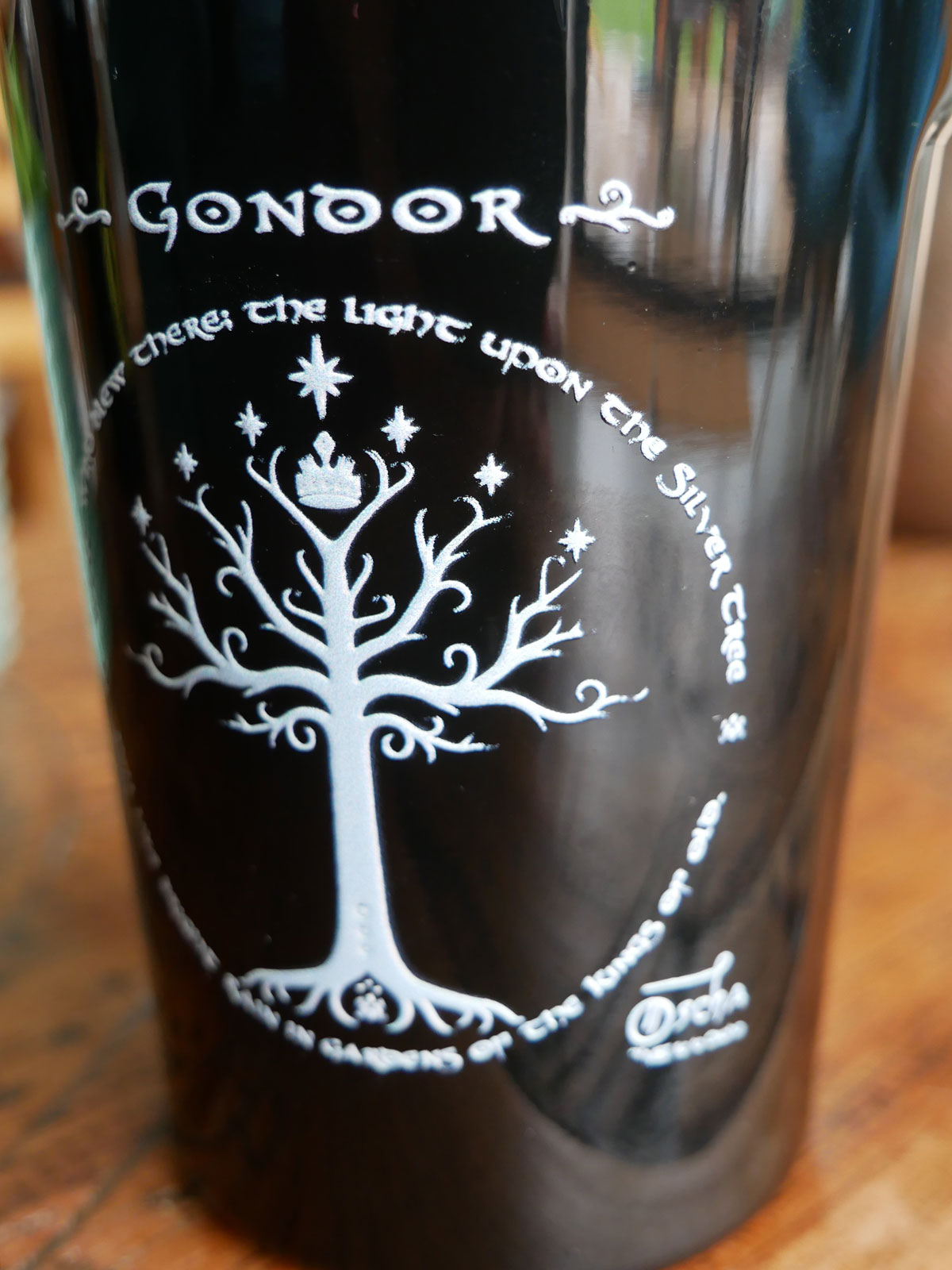 Black travel mug with white tree design and 'Gondor' text on a wooden surface