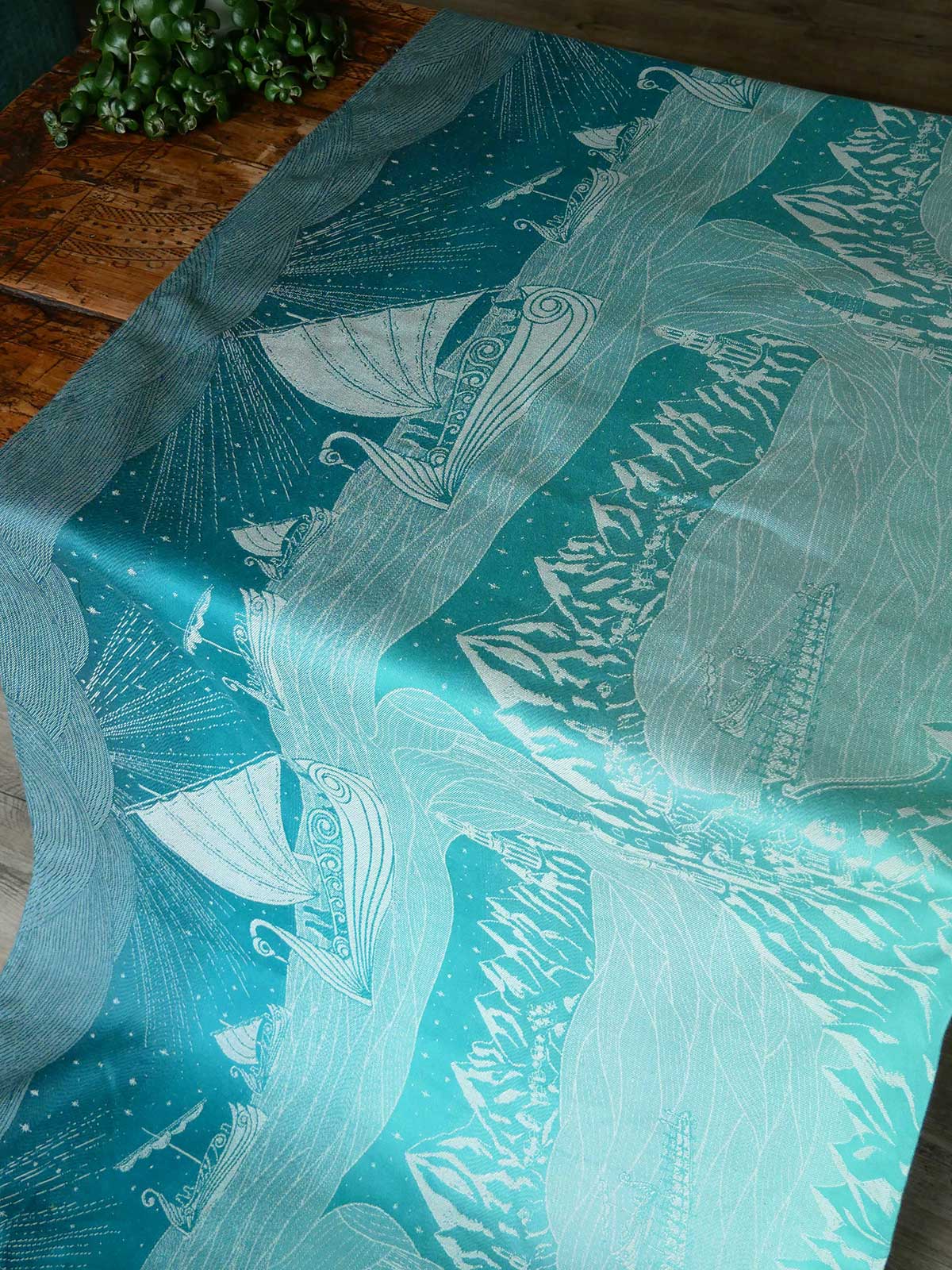 Teal fabric with white sailboat pattern on a wooden surface