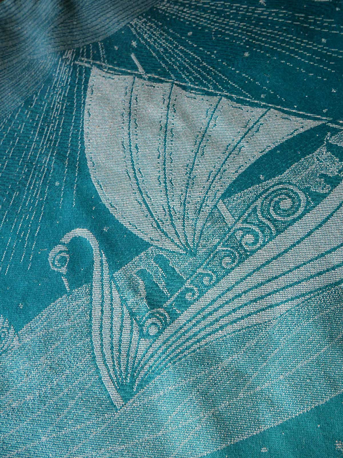 Close-up of a textured fabric with a stylized sailboat design on a teal background