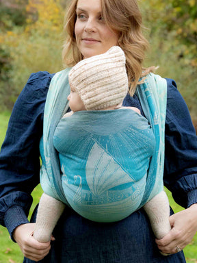 Woman holding a baby in a Grey Havens into the West Woven Wrap outdoors.