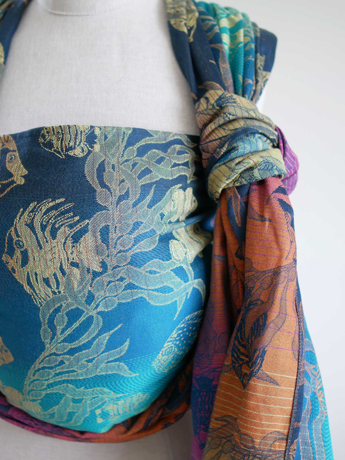 A blue teal woven wrap with tropical fish patten on a mannequin