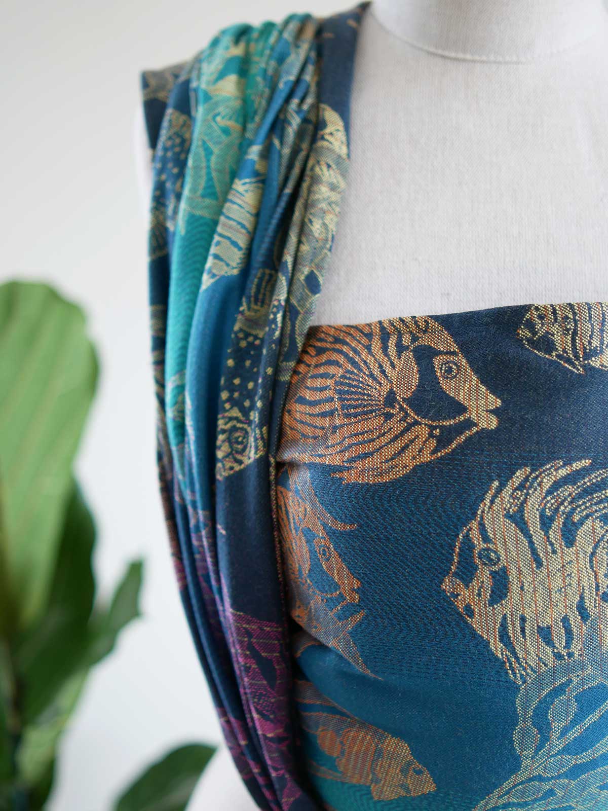 Close up of a blue teal woven wrap with tropical fish patten on a mannequin