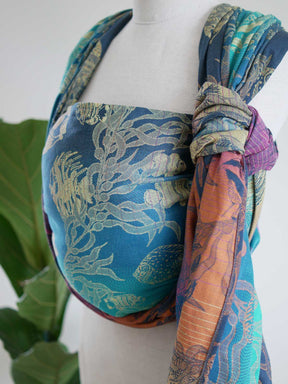 A blue teal woven wrap with tropical fish patten on a mannequin