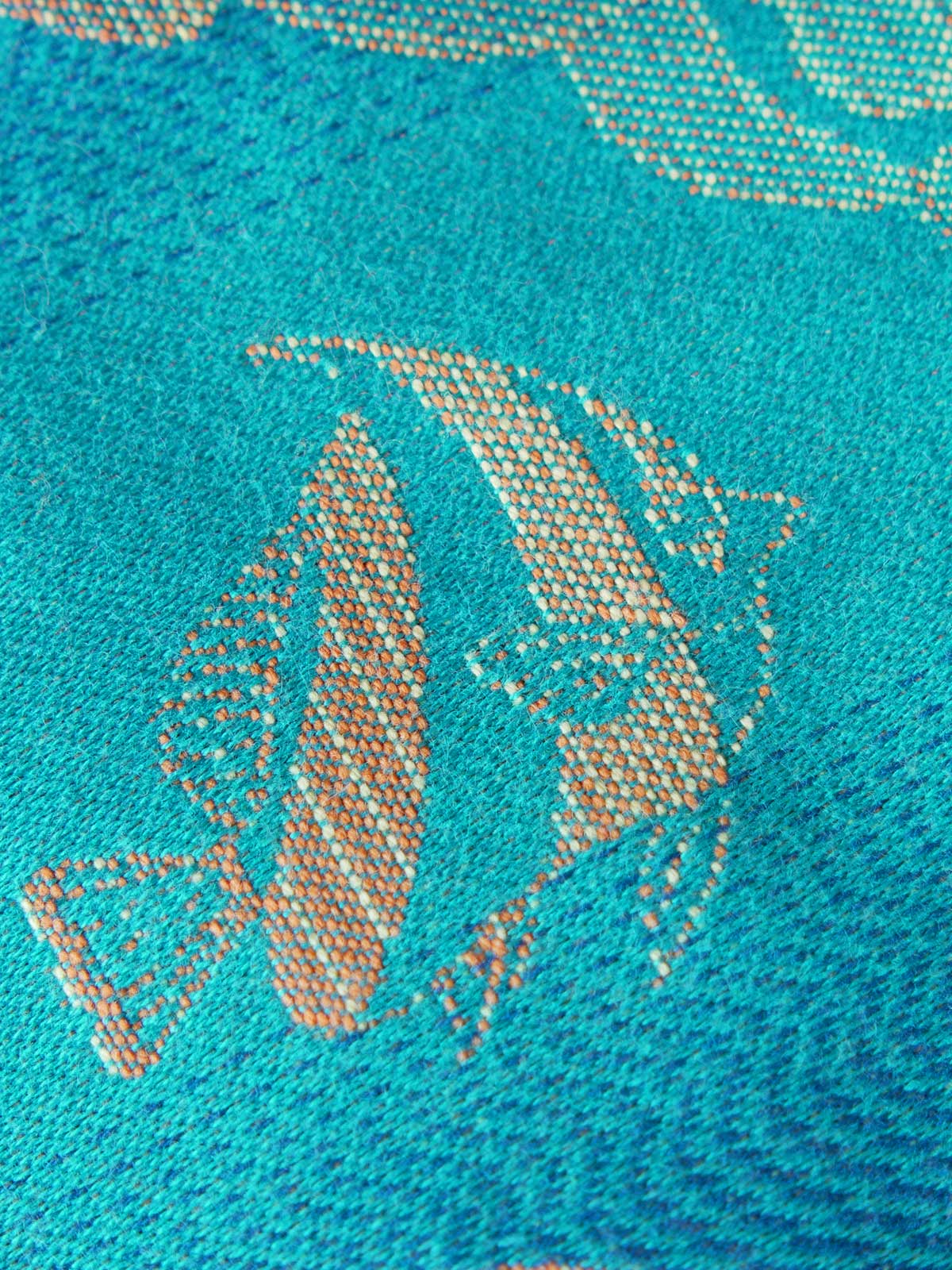 Close up of a blue teal fabric with tropical fish patten in gold