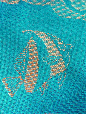 Close up of a blue teal fabric with tropical fish patten in gold