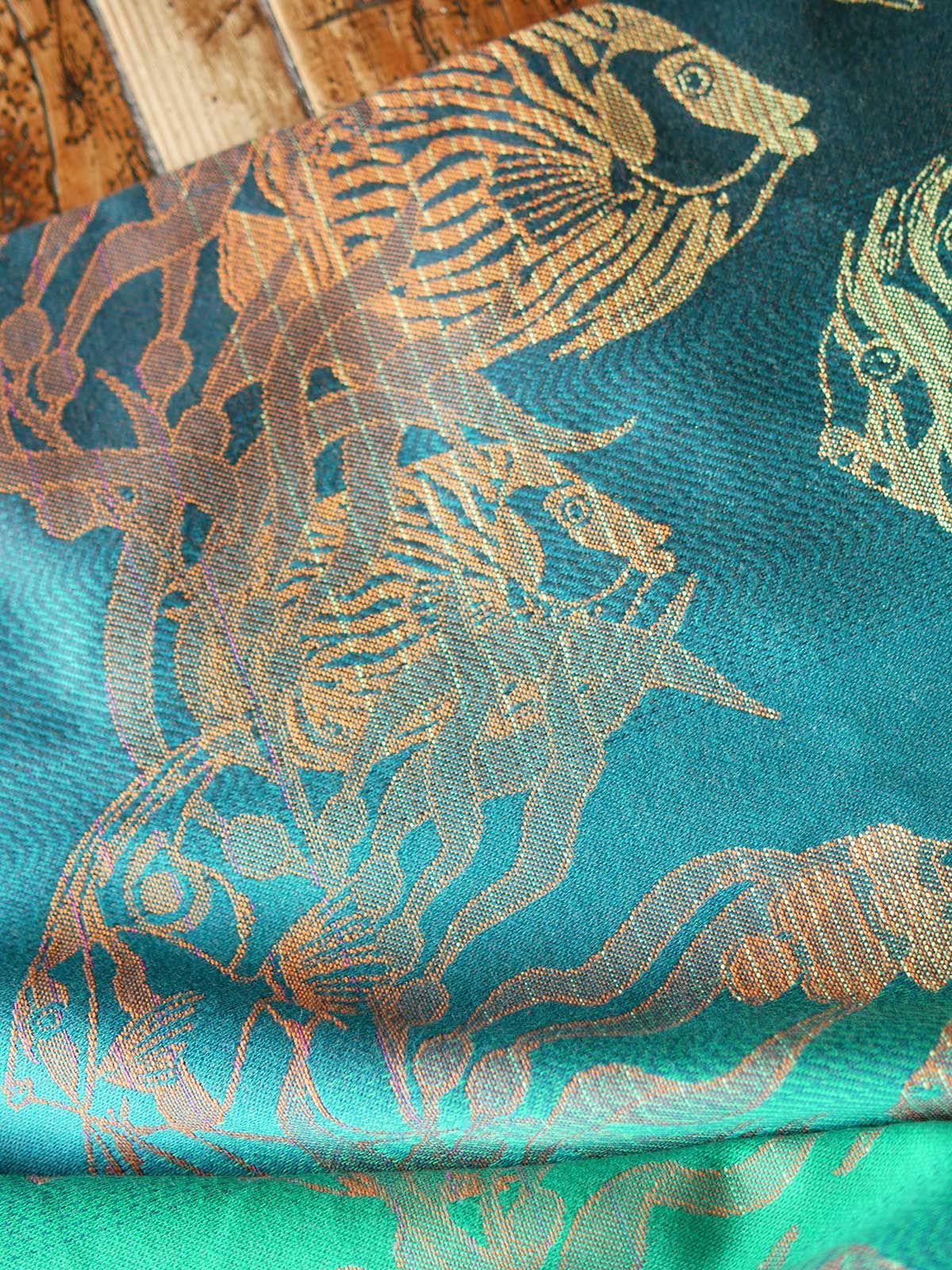 Close up of a blue teal fabric with tropical fish patten in gold and orange
