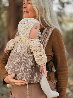 Woman holding a baby in a carrier outdoors