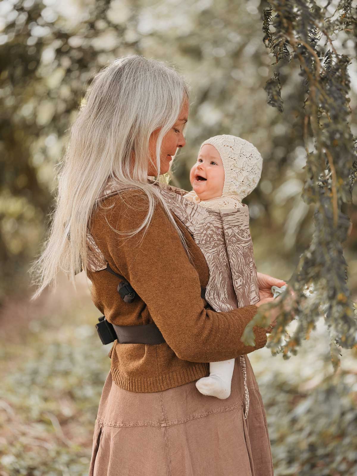Woman and baby in a carrier outdoors.