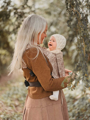 Woman and baby in a carrier outdoors.