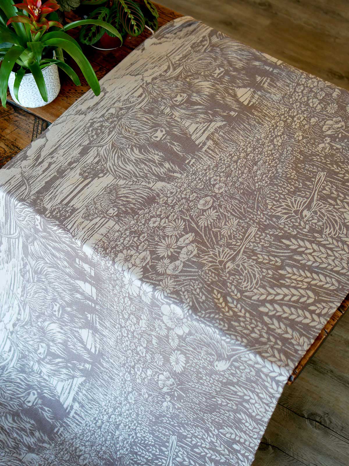 Patterned fabric with a highland cow themed design on a wooden surface