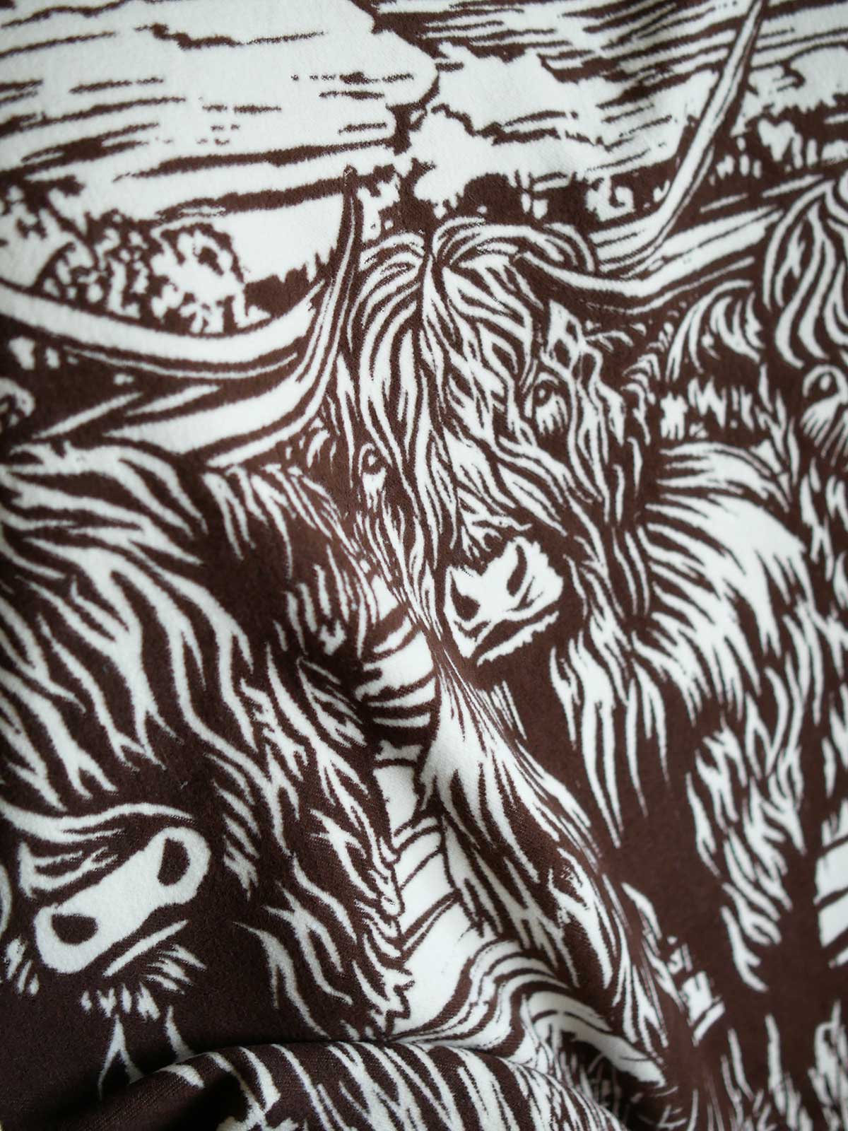 Close up of a brown throw with highland cow design