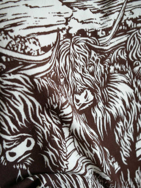 Close up of a brown throw with highland cow design