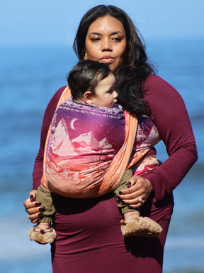 Model with baby in a wrap and sea view in the background. 