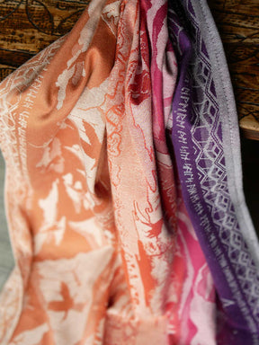 Fabric draping over table showing the colours flowing from orange to pink to purple. Features runes based on The Lord of the Rings. 