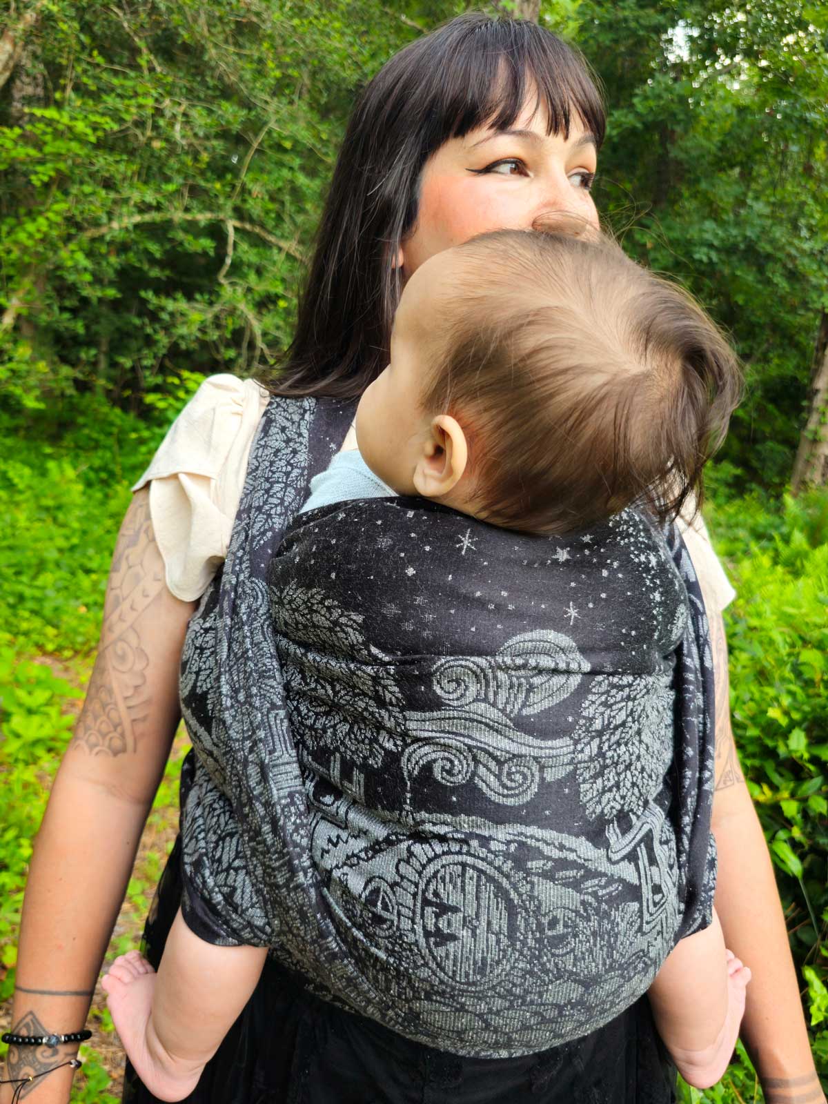 Woman wearing a baby in a black woven wrap on her front