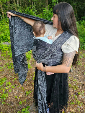 Woman wrapping a baby in a black woven wrap on her front