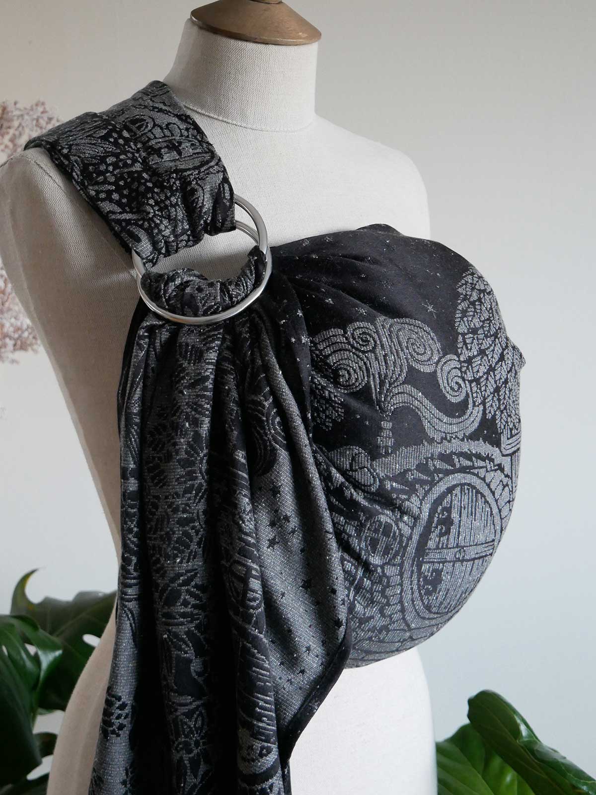 Side profile of black ring sling on a mannequin with silvery hobbit house design