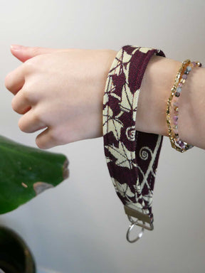 Hand wearing a patterned keyring with a plain background.