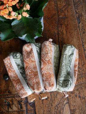 Four patterned pouches on a wooden surface with a plant in the corner.