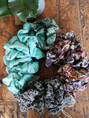 Group of of scrunchies in different fabrics on wooden table.