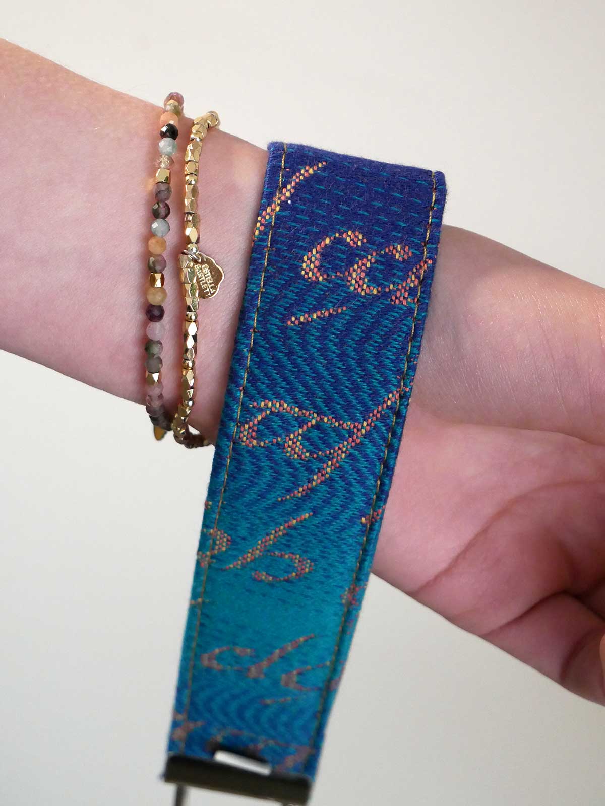 Blue woven bracelet on a wrist with a plain background