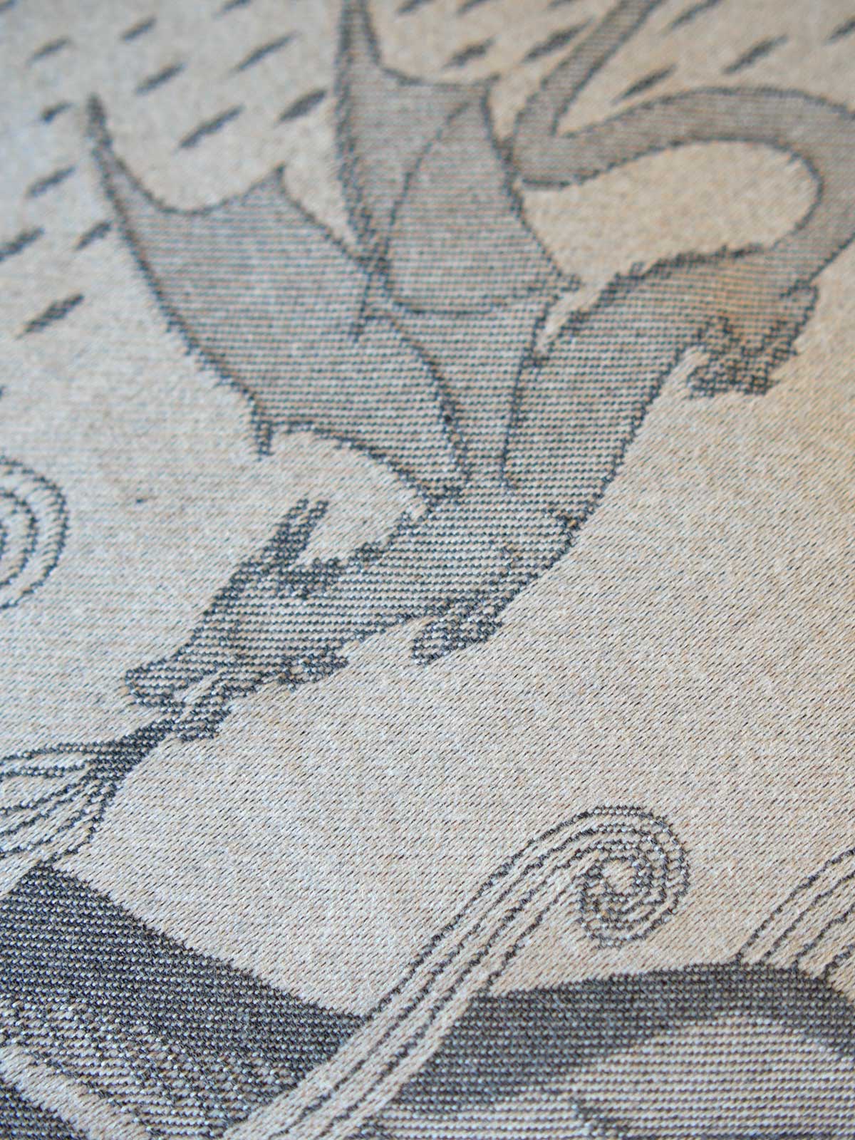 Close-up of a woven textile pattern featuring a gray dragon on a warm beige background.