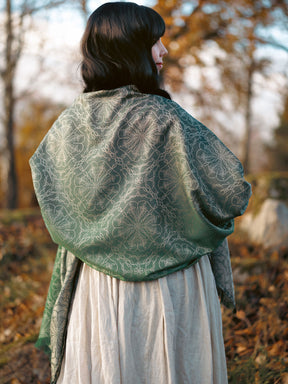 Person wearing a green patterned shawl in a forest setting