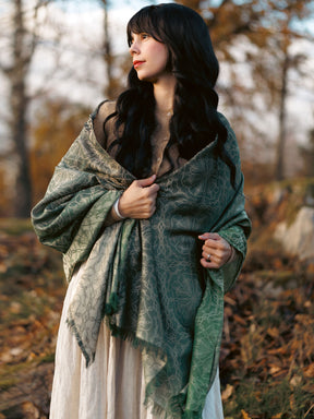 Woman wearing a green patterned shawl in a forest setting