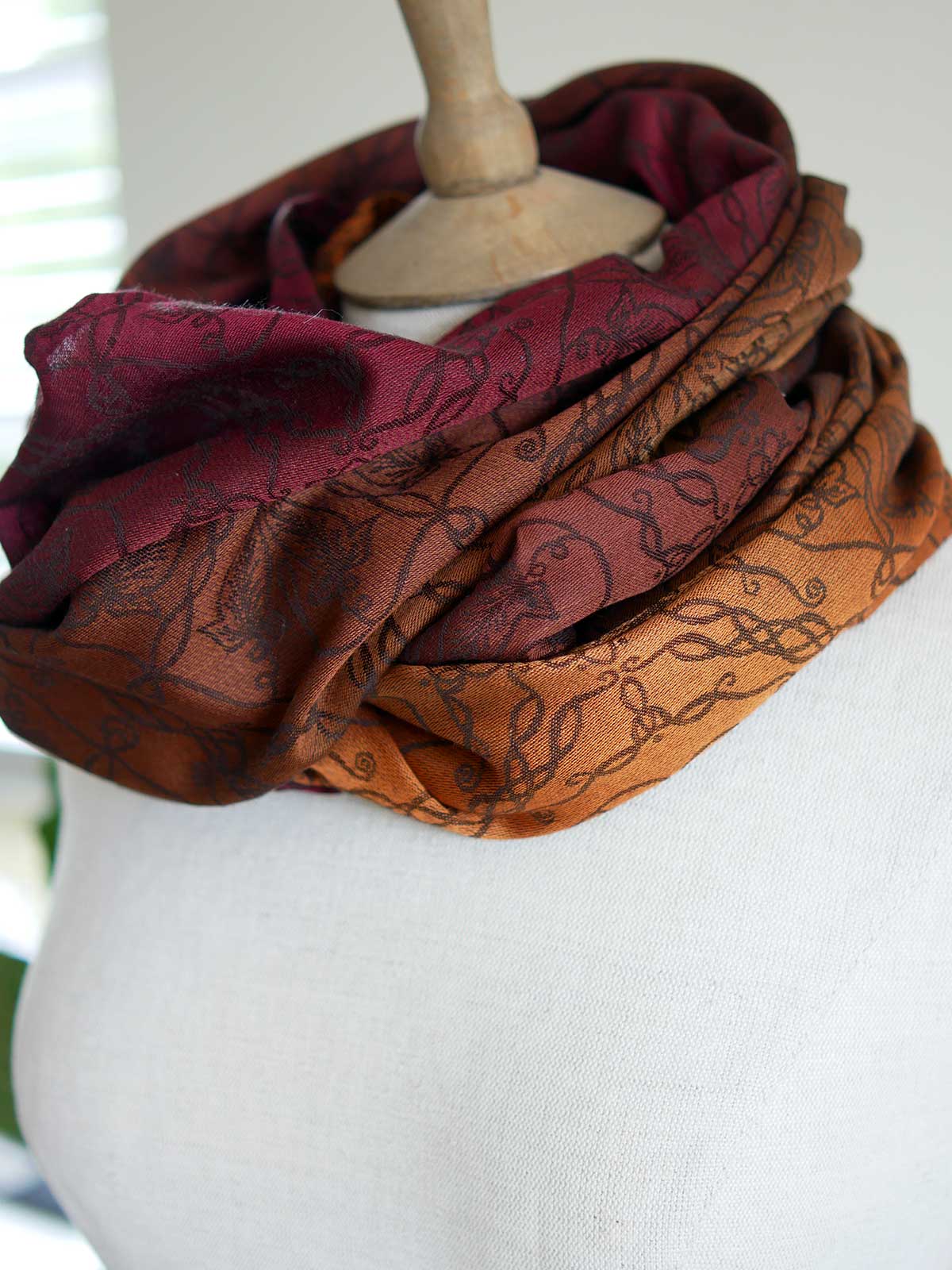 Red and carmel coloured infinity loop, looped twice on a mannequin.