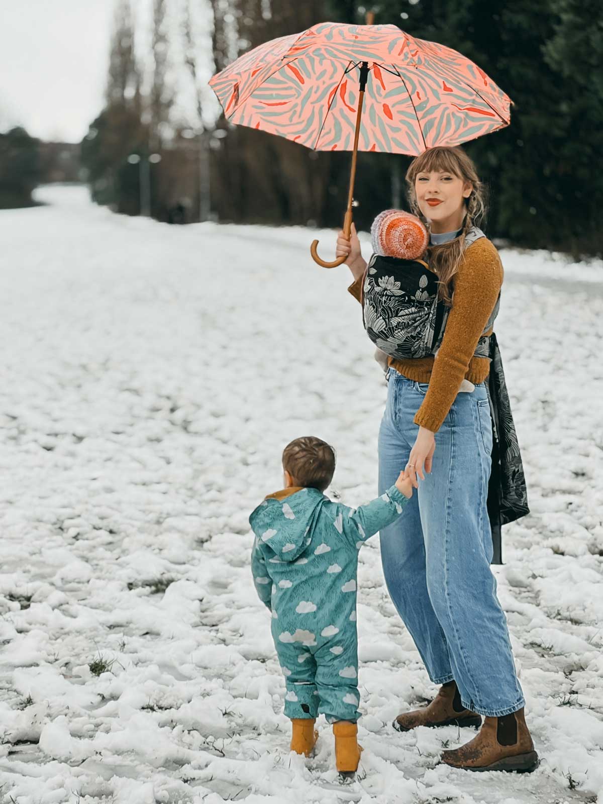 Woman holding an umbrella and a child in a snowy landscape