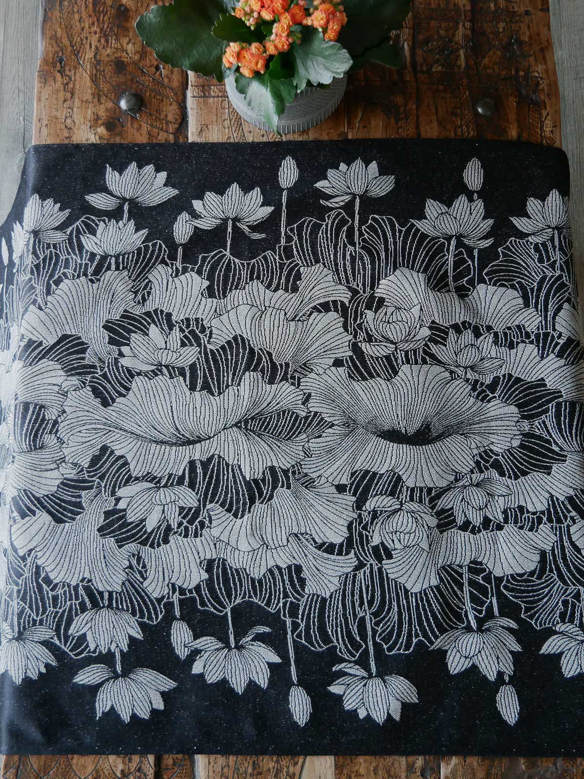 Floral patterned fabric on a wooden surface with a small plant.
