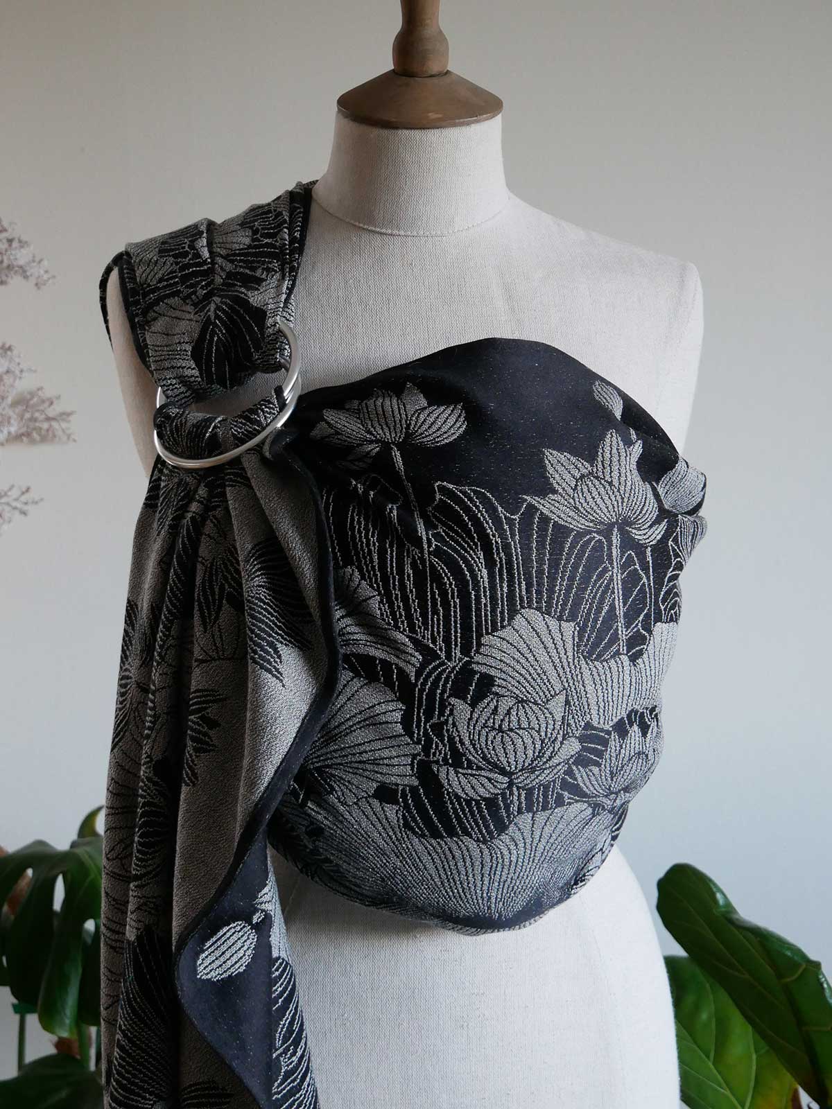 Black floral patterned baby carrier on a mannequin with a white background