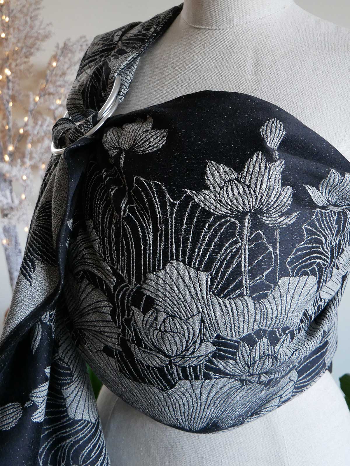 Black floral ring sling draped over a mannequin with a blurred decorative background