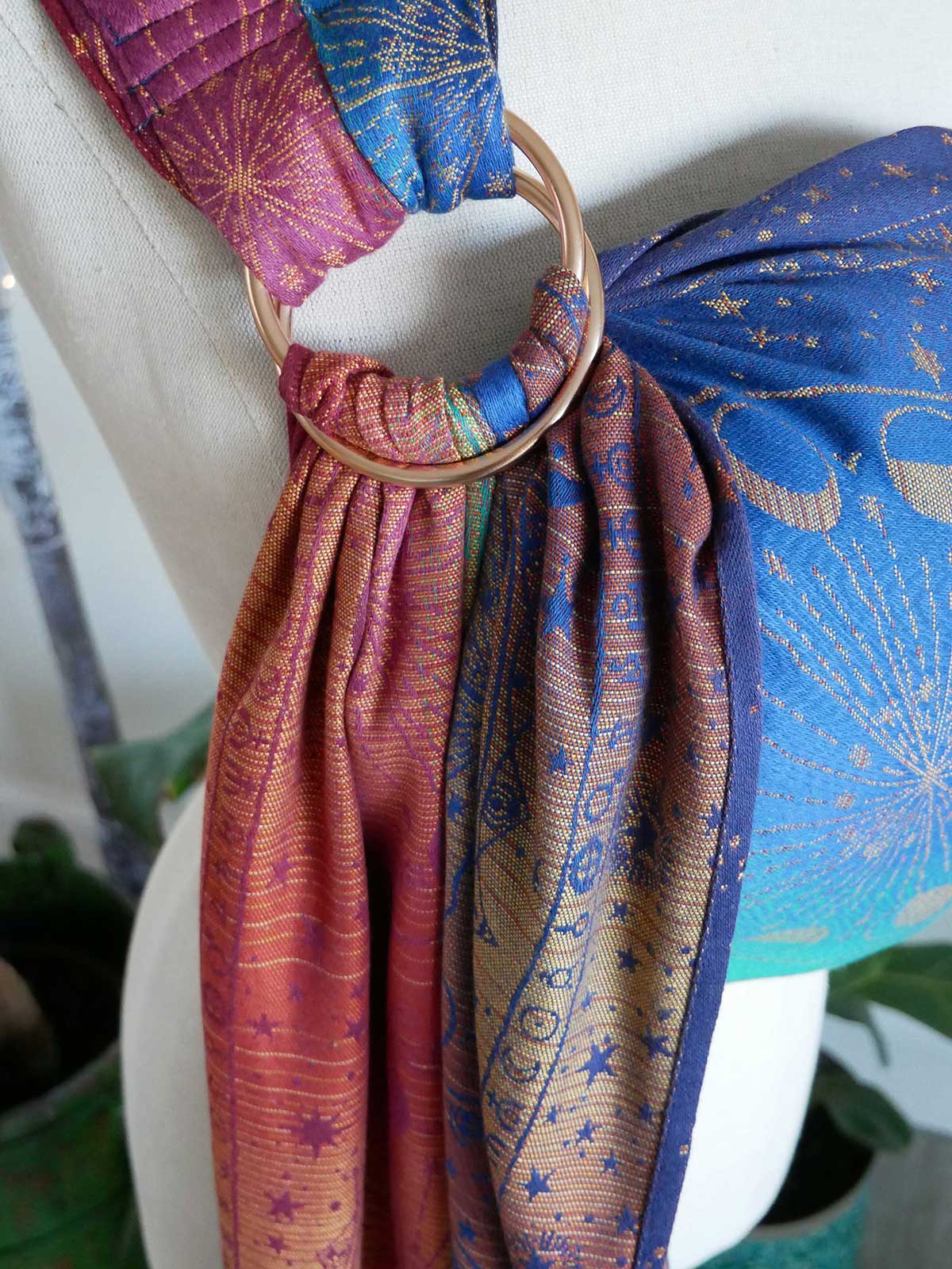Multicoloured ring sling on a white mannequin against a blurred indoor background