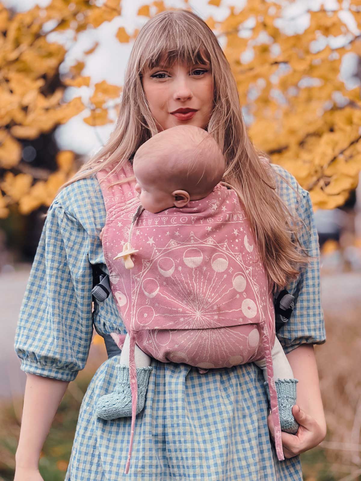 Model wears Oscha slings Bairn baby carrier in dusky pink. 