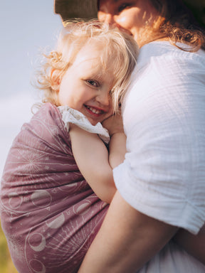 Woman holding a child in a sling with a blurred background
