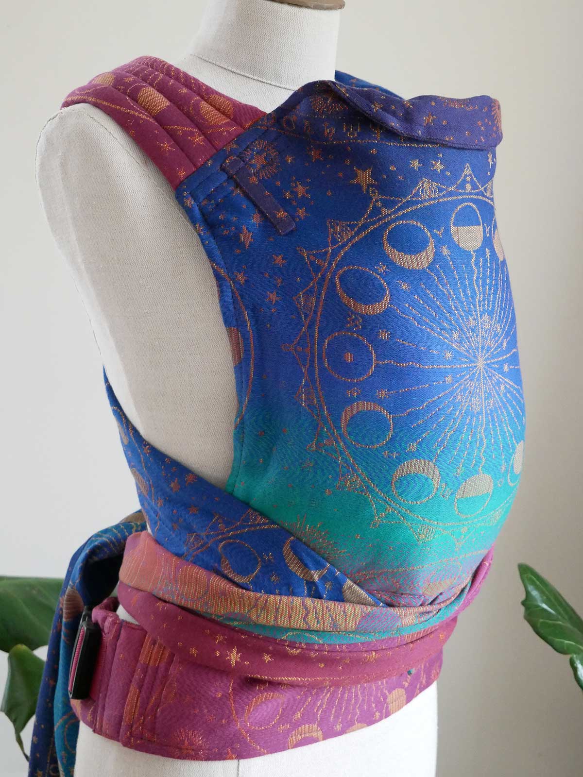 Mannequin wearing a colourful baby carrier with celestial design