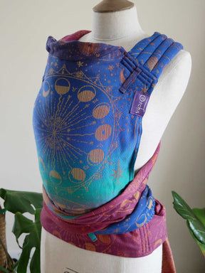 Colourful baby carrier with celestial design on a mannequin against a neutral background