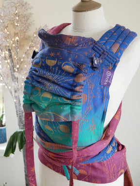 Colouful baby carrier on a mannequin with a decorated tree in the background